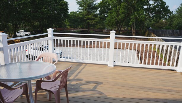 A wooden deck with a white fence, a round table, and two chairs. - 2nd floor Downtown Apartment  (Gettysburg)