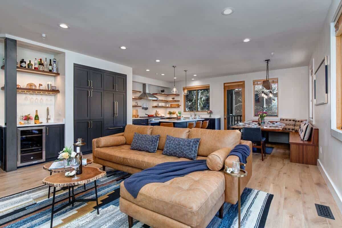 A modern living room with a sofa, coffee table, and a dining area with a bench.