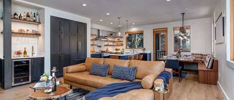 A modern living room with a sofa, coffee table, and a dining area with a bench.