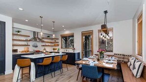Une cuisine moderne dotée d’un îlot central, de tabourets de bar et d’une table à manger avec des chaises.