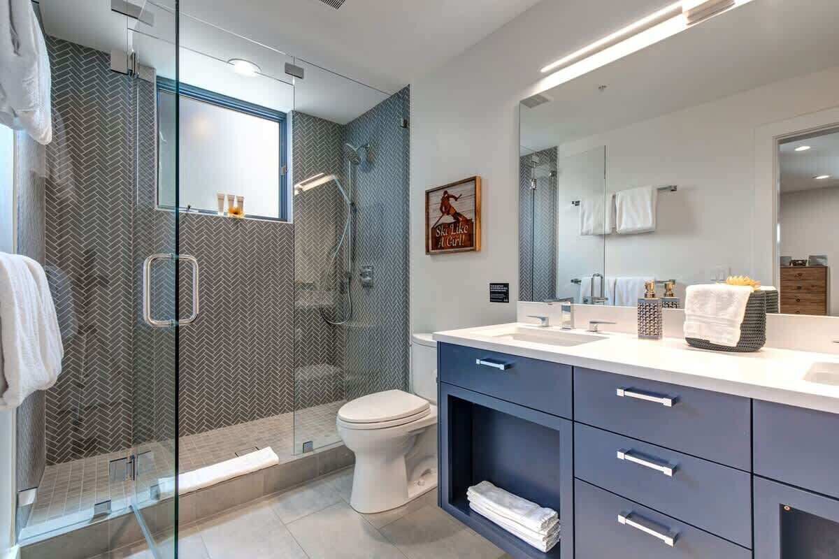 Een moderne badkamer met een douchecabine van glas, een wit toilet en een wastafel met spiegel.