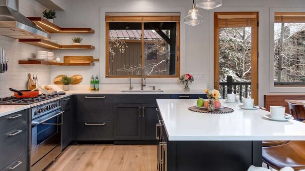 Une cuisine moderne avec des meubles de couleur sombre, un îlot central et des étagères en bois.