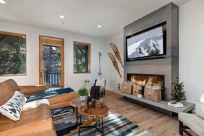 A modern living room with a fireplace, large windows, and a television.