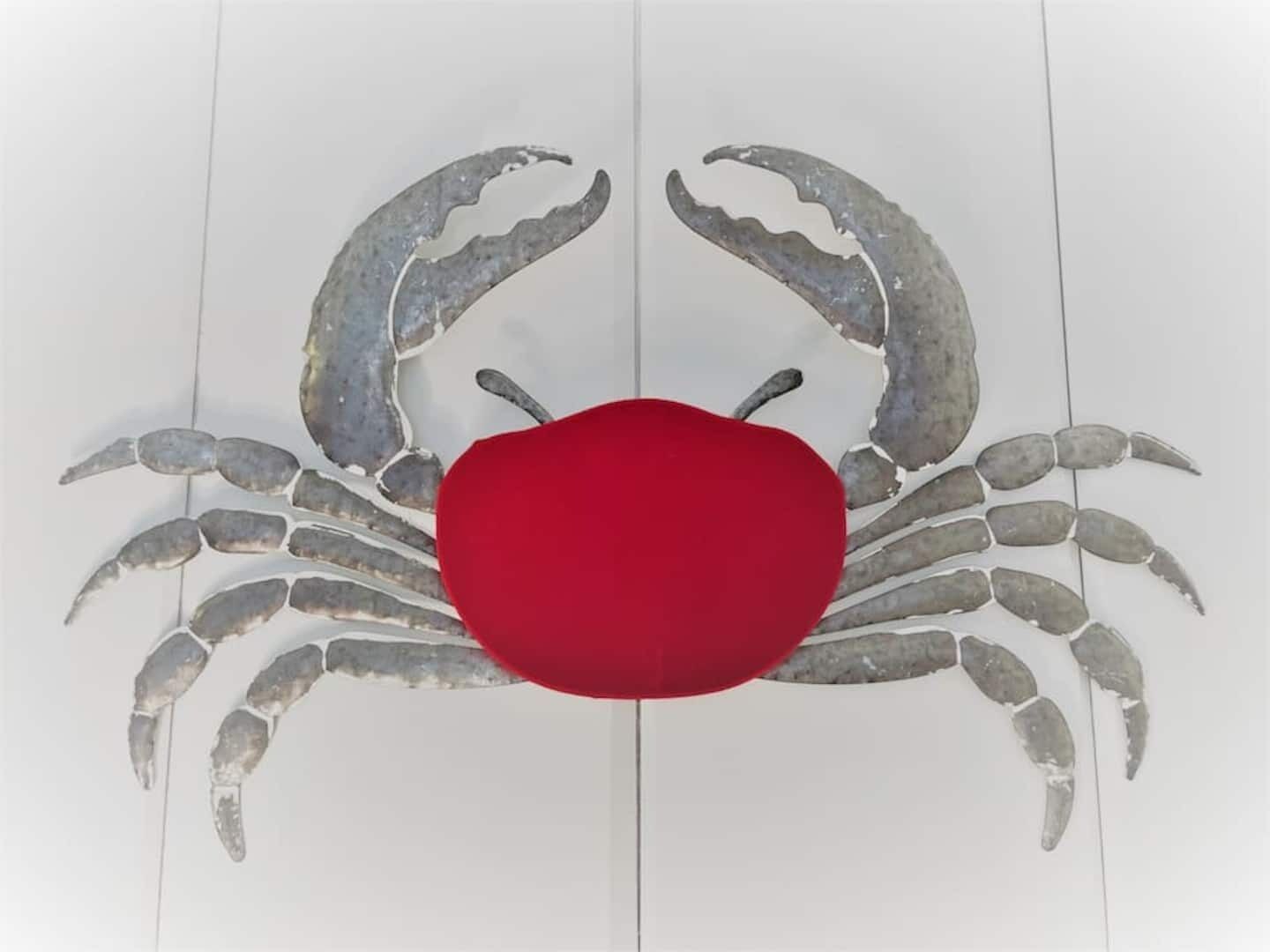 Une décoration en forme de crabe, avec un centre rouge sur un fond blanc.