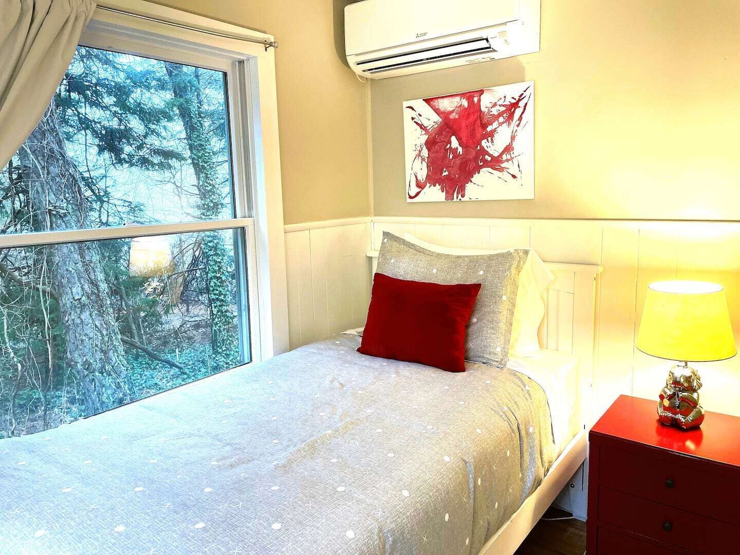 A bedroom with a bed, a nightstand, a lamp, and a painting on the wall.