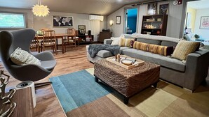 A modern living room with a grey sofa, a wooden coffee table, and a dining area with a wooden table and chairs. - Funky Upstairs apartment - steps from local popular restaurant. (Arundel)
