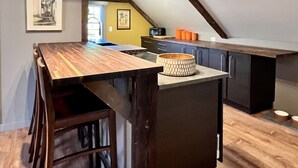 A modern kitchen with a wooden island, dark cabinetry, and a hanging light fixture. - Funky Upstairs apartment - steps from local popular restaurant. (Arundel)