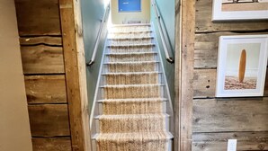 A staircase with a textured carpet, wooden walls, and framed pictures on the walls. - Funky Upstairs apartment - steps from local popular restaurant. (Arundel)