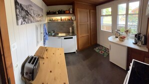 Een compacte keuken met witte kasten, een houten aanrecht, een broodrooster en een raam met uitzicht op groen.