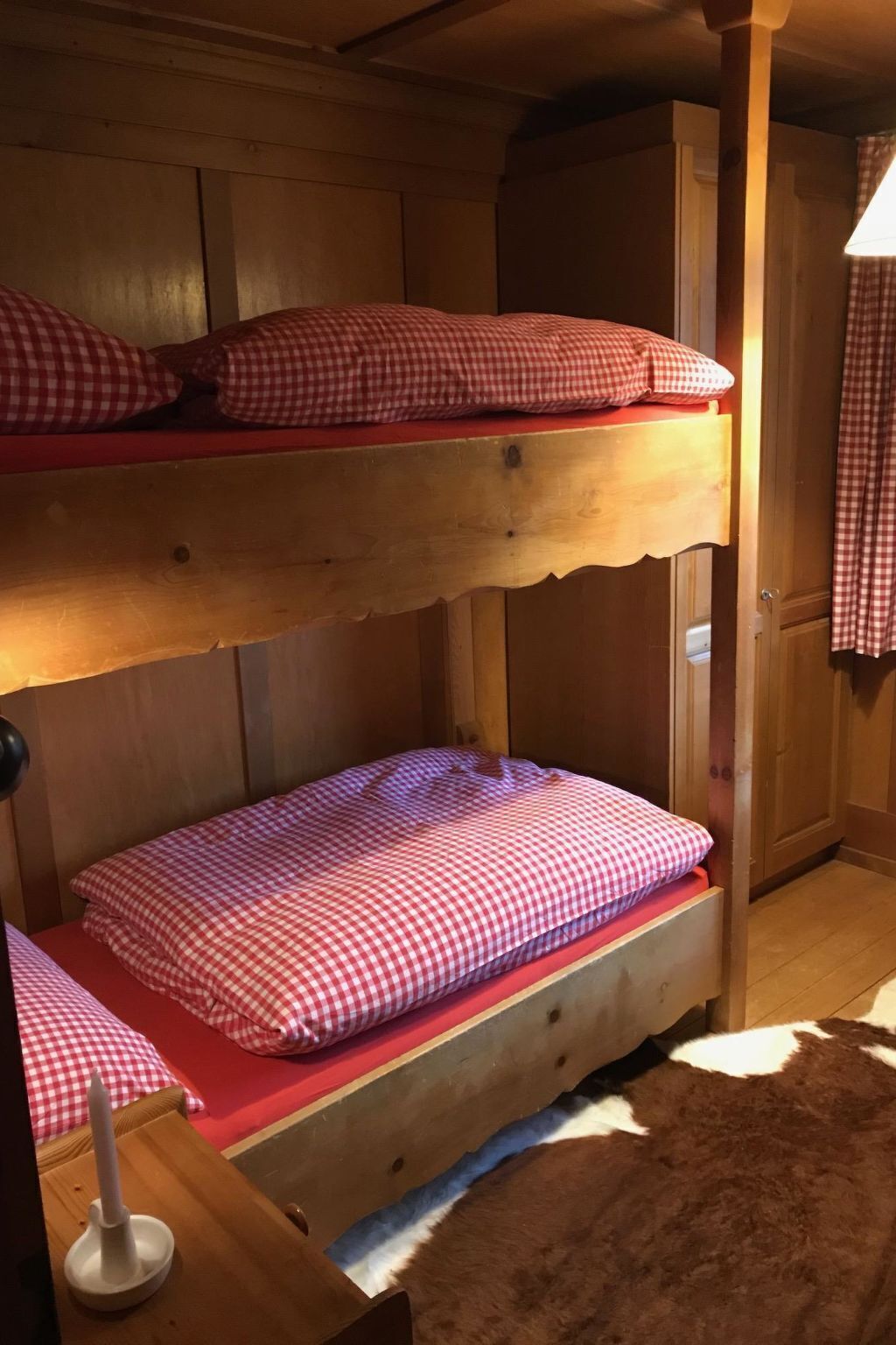Camera con letto a castello, biancheria a scacchi e pavimento in legno.
