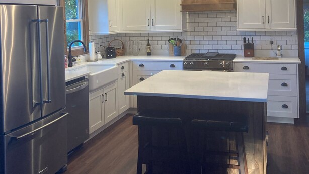Una cocina moderna con armarios blancos, electrodomésticos de acero inoxidable y techo de madera.