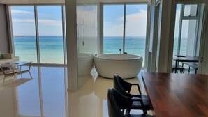 A modern room with a large wooden table, black chairs, and a view of the ocean through large windows. - Daytona Pool Villa (Pohang)