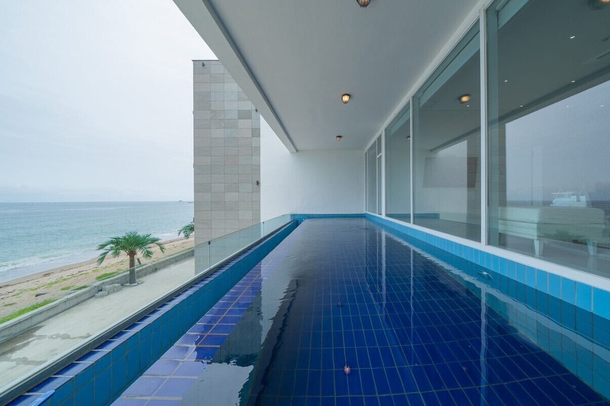 A long, narrow indoor pool with a view of the beach and ocean.