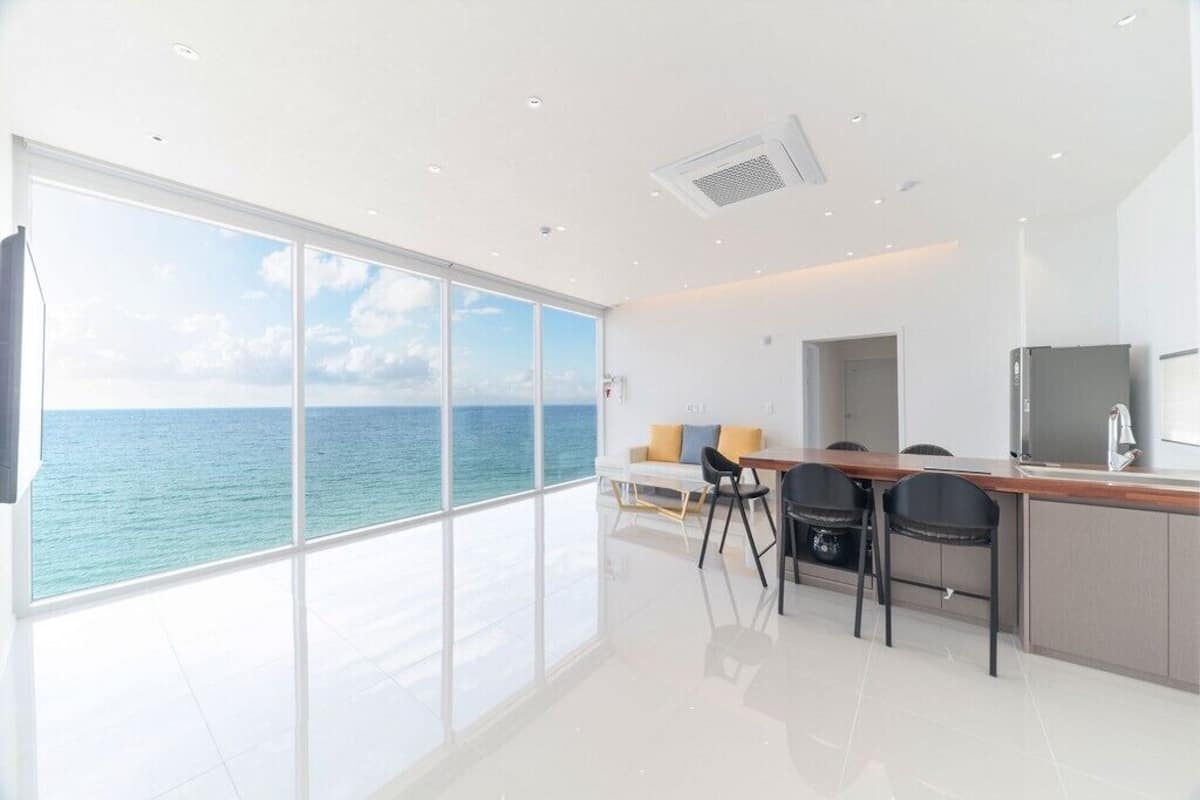 A modern kitchen with a view of the ocean, a dining area with chairs, and a small table.