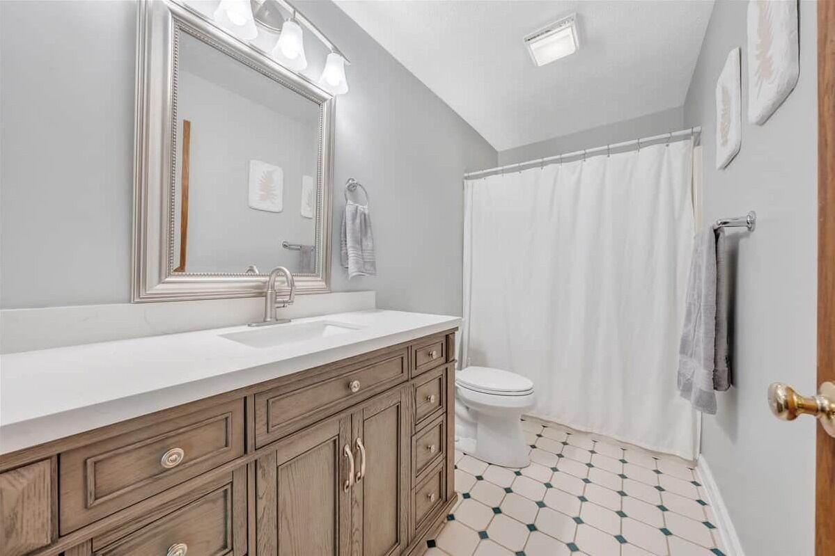 Une salle de bain avec un grand miroir, un lavabo et des toilettes.