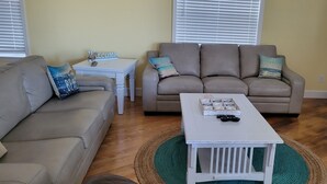 A living room with two sofas, a coffee table, and a small white table with a 'Welcome' sign. - Beach house within walking distance to the beach  2 bed 2 bath (Jensen Beach)