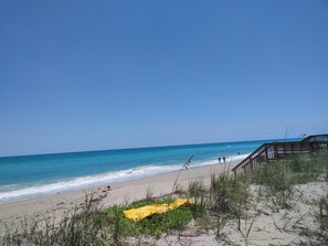 Enjoy a serene beachside stroll along the boardwalk, where the calm sea meets the sandy shore.