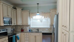 A kitchen with wooden flooring, white cabinets, a stainless steel refrigerator, and a microwave. - Beach house within walking distance to the beach  2 bed 2 bath (Jensen Beach)
