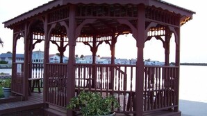 A wooden gazebo with a balcony, situated near a body of water. - Beach house within walking distance to the beach  2 bed 2 bath (Jensen Beach)
