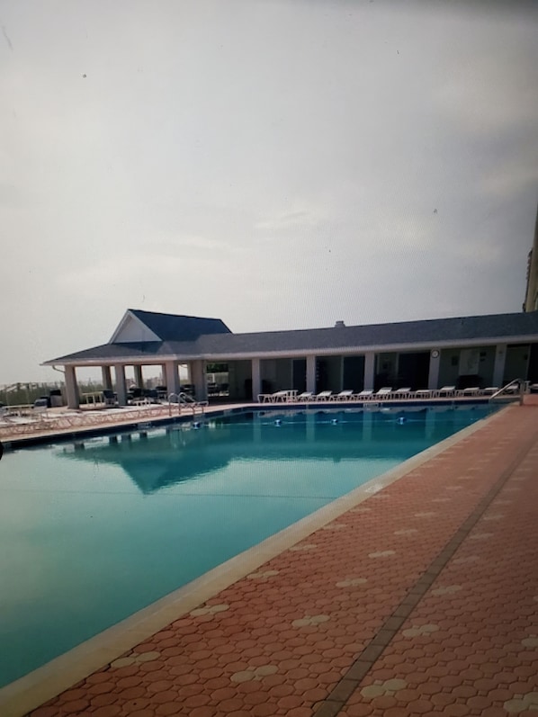 A swimming pool with a covered area and lounge chairs. - Beach house within walking distance to the beach 2 bed 2 bath (Jensen Beach)