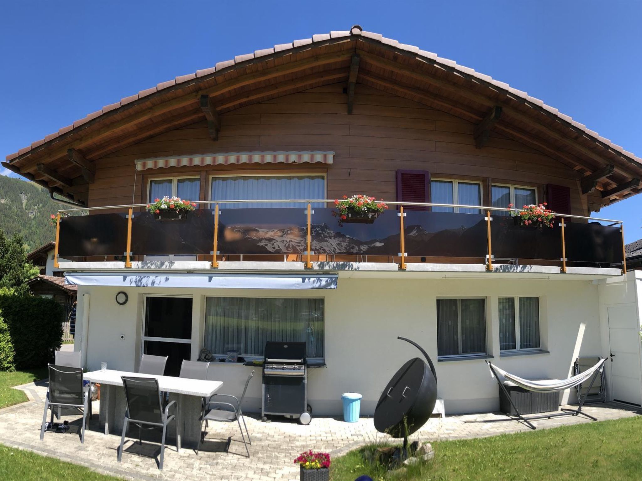 Eine zweistöckige Chalet mit Balkon, Sitzgelegenheit im Freien und Grillplatz.
