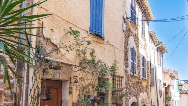 A narrow street with traditional stone buildings, a wooden door, and hanging plants. - Vacation home La Roq by Interhome (Roquebrune sur Argens)