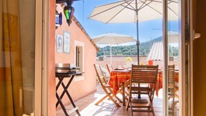 An open patio with a table and chairs, a large umbrella, and a view of a hillside. - Vacation home La Roq by Interhome (Roquebrune sur Argens)