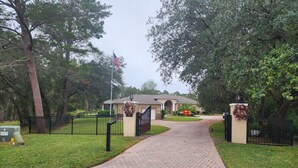 A paved driveway leading to a gated entrance with a house in the background. - Beautiful 2Bed,2Bath,2Car Garage Stunning Cul-de-sac property on 2 acres Estate (Spring Hill)