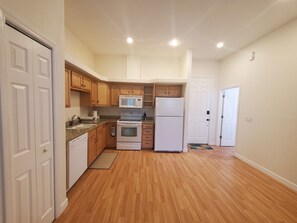 A kitchen with wooden cabinets, a microwave, a refrigerator, and an oven.