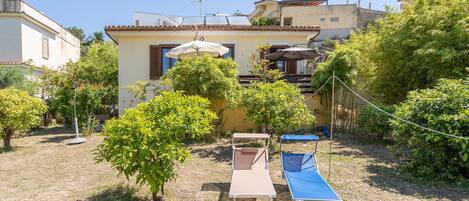 A villa with a garden, outdoor seating, and a solar panel on the roof.