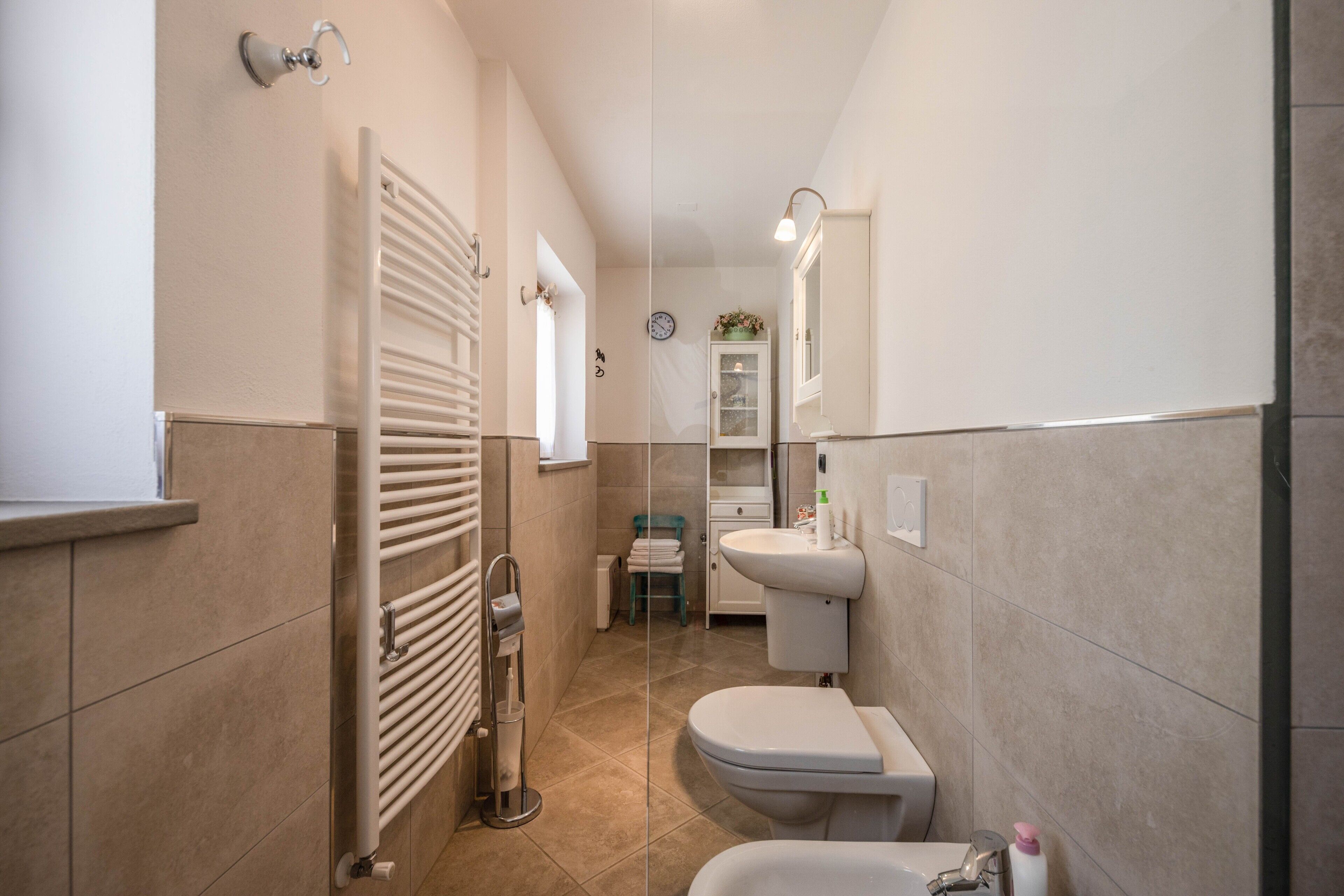 Ein schmales Badezimmer mit Toilette, Waschbecken und Handtuchhalter.