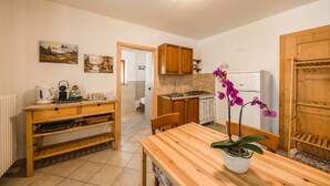 A kitchen with wooden cabinets, a dining table with chairs, a refrigerator, and a potted orchid.
