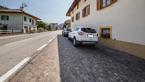 A street with buildings, a paved sidewalk, and parked cars.