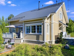A two-story house with a covered patio area, a hot tub, and a deck with outdoor furniture.