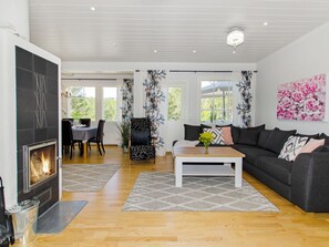 A modern living room with a fireplace, a dining area, and a sofa.