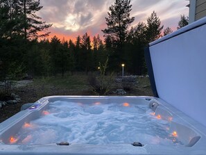 A hot tub outdoors with a sunset in the background.