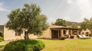 A house with a patio, a tree, and a lawn. - Holiday Home "Asfodeli" with Wi-Fi, A/C & Garden (Teulada)