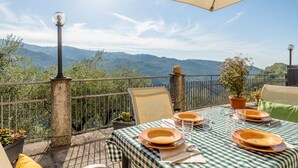 Une terrasse avec une table dressée pour deux personnes, offrant une vue sur un paysage montagneux.