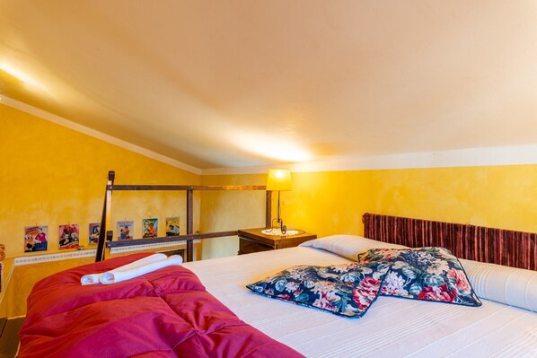 Una habitación con una cama, una mesita de noche, una lámpara y carteles en la pared.