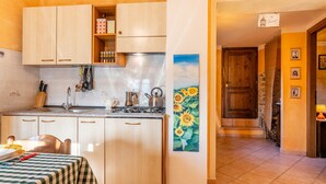 Une cuisine avec des meubles de rangement en bois, une cuisinière et un évier. Un tableau représentant des tournesols est accroché au mur.
