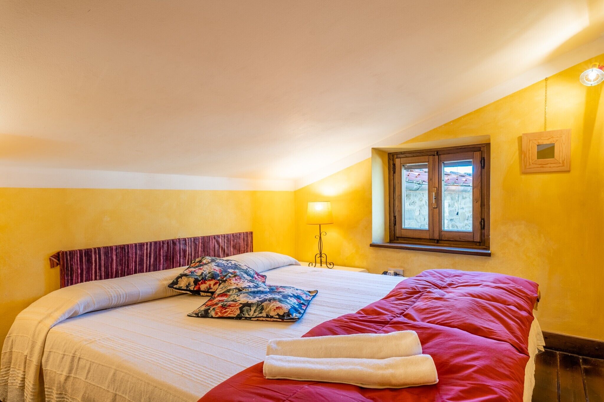 Une chambre à coucher avec un lit, des oreillers, une lampe et une fenêtre.