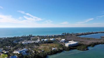 An aerial view of a coastal resort with multiple buildings, a marina, and a clear view of the ocean.