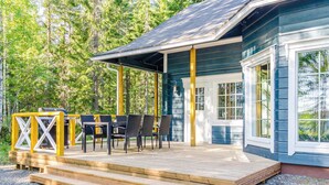 Une terrasse en bois avec des sièges pour l’extérieur et un porche abrité.