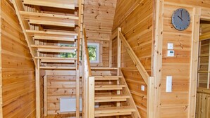 Un intérieur en bois avec un escalier, des murs en bois et une horloge.
