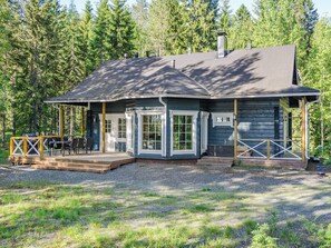 Une cabane dotée d’une terrasse, de grandes fenêtres et d’une cheminée.