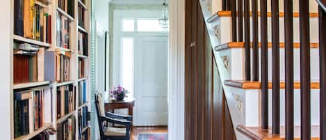 A narrow hallway with wooden bookshelves on one side and a wooden staircase on the other.