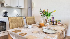 A dining area with a table set for two, featuring a patterned tablecloth, wicker chairs, and a vase with flowers. - Casa Stella App. 1 by Interhome (Brissago)