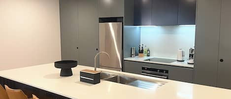 A modern kitchen with a large island, stainless steel appliances, and bar stools.