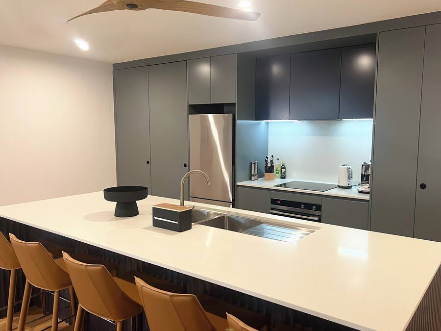A modern kitchen with a large island, stainless steel appliances, and bar stools.