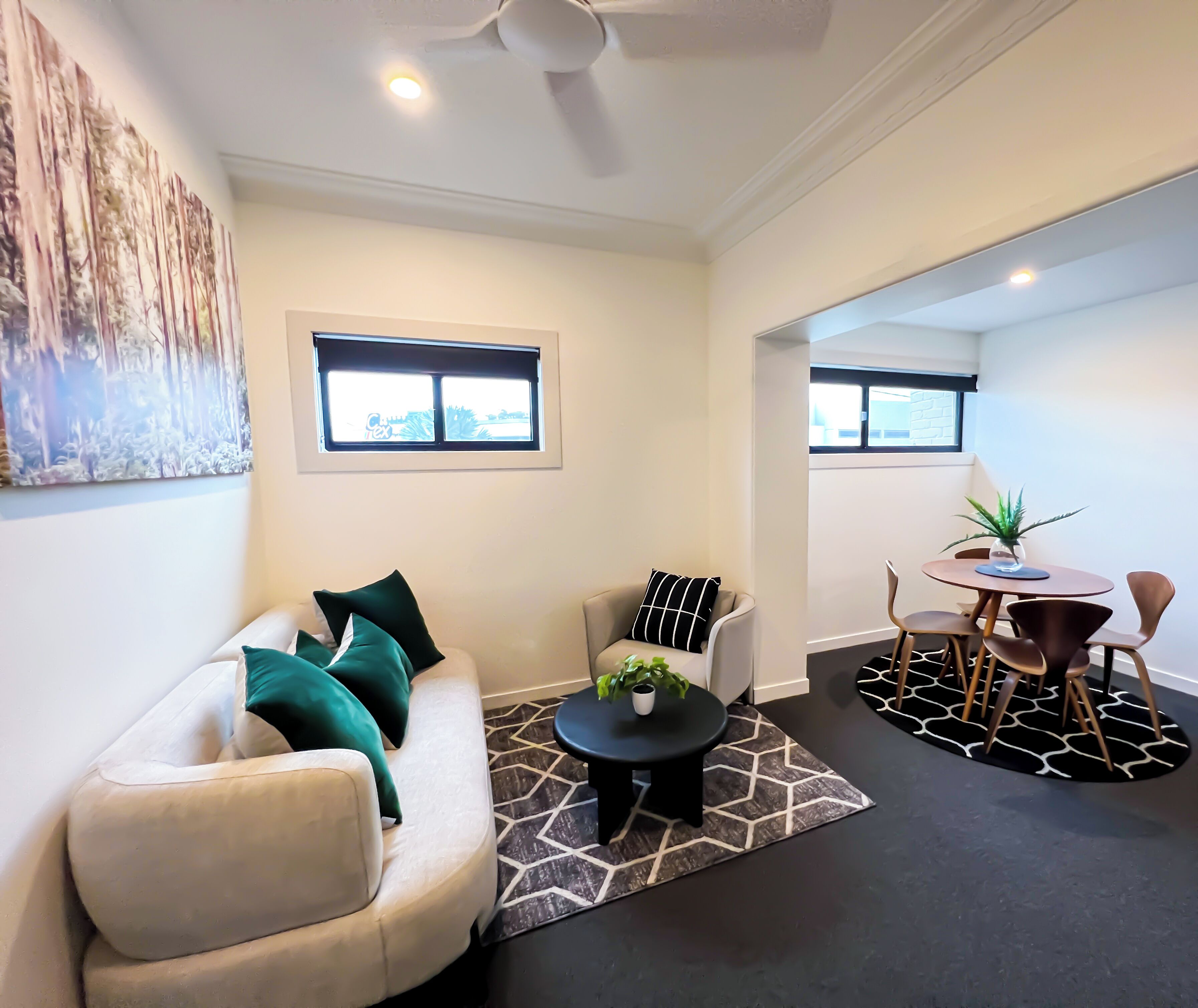 A living room with a sofa, coffee table, and a dining area with chairs and a table.